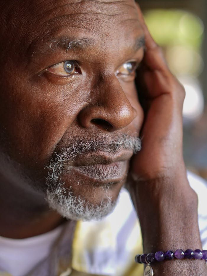 Close-up portrait of a senior black man looking thoughtful and emotional.
